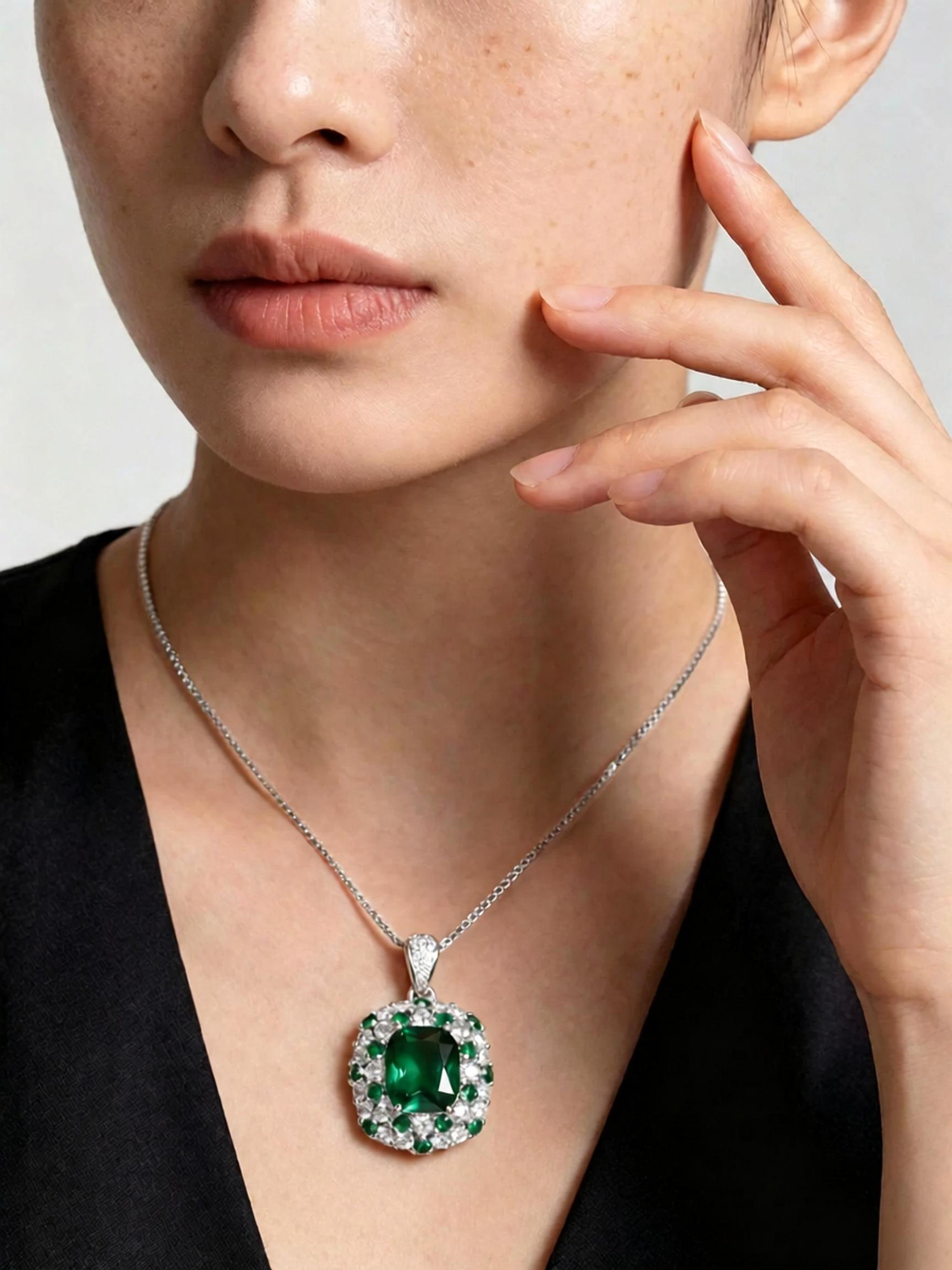 Emerald journey pendant necklace close‑up, green emerald surrounded by sparkling zircon frame