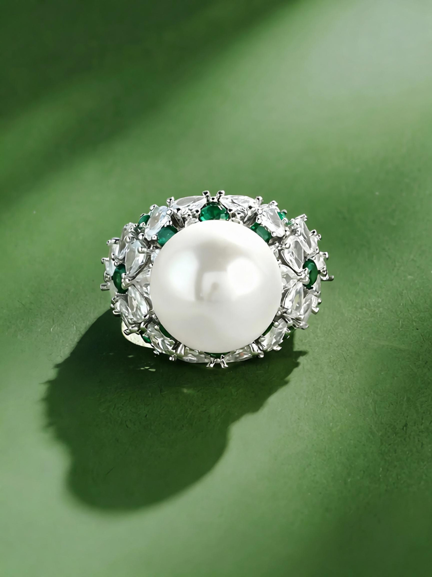 Floating pearl ring front detail, smooth round pearl with sparkling emerald green zircon accents