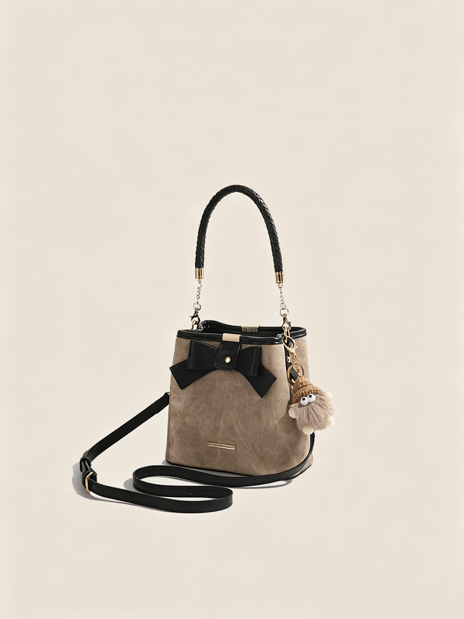 Front view of grey textured suede bucket bag with black leather bow detail