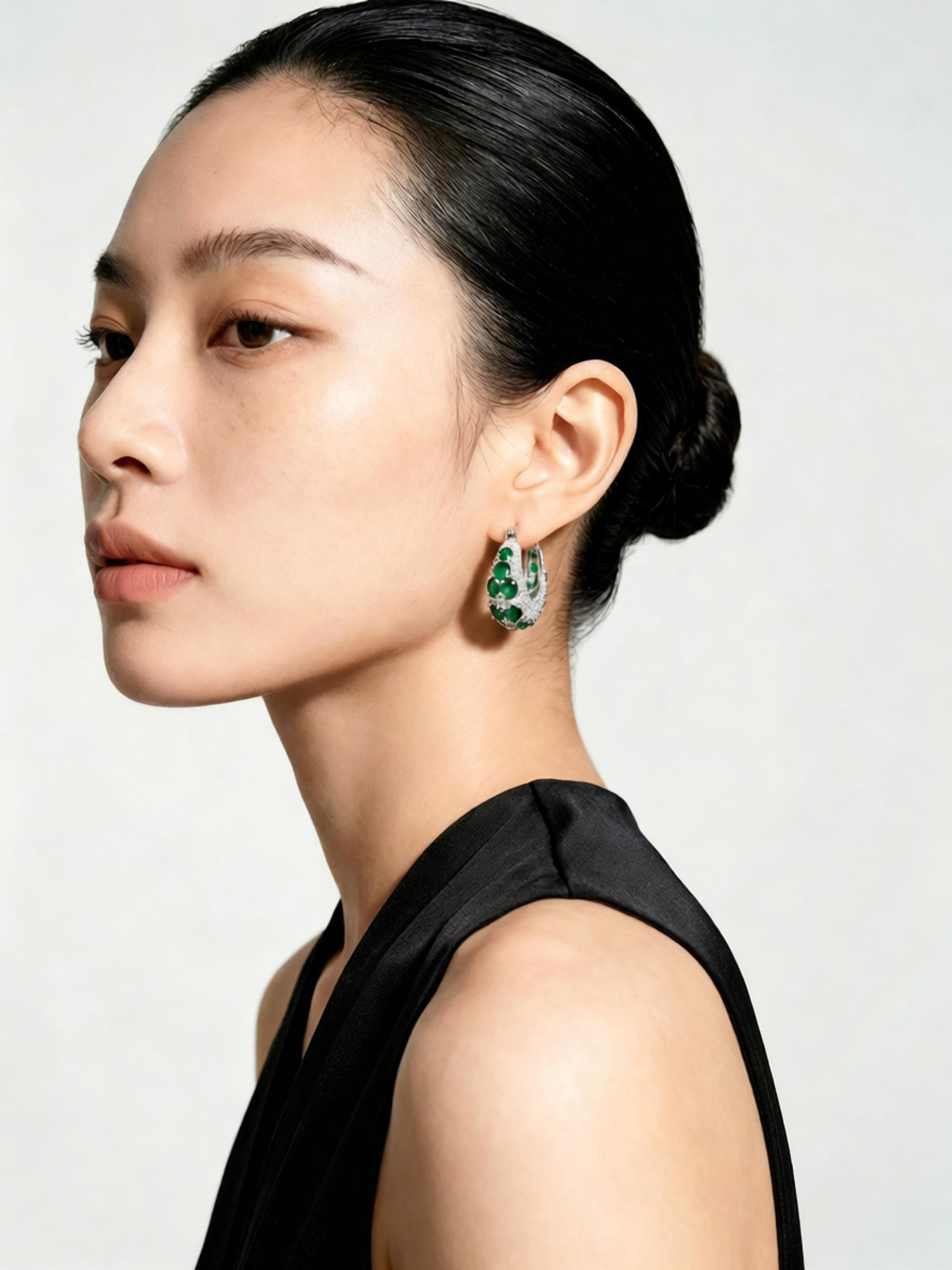 Macro detail of prong‑set emerald zircon on green galaxy hoop earring